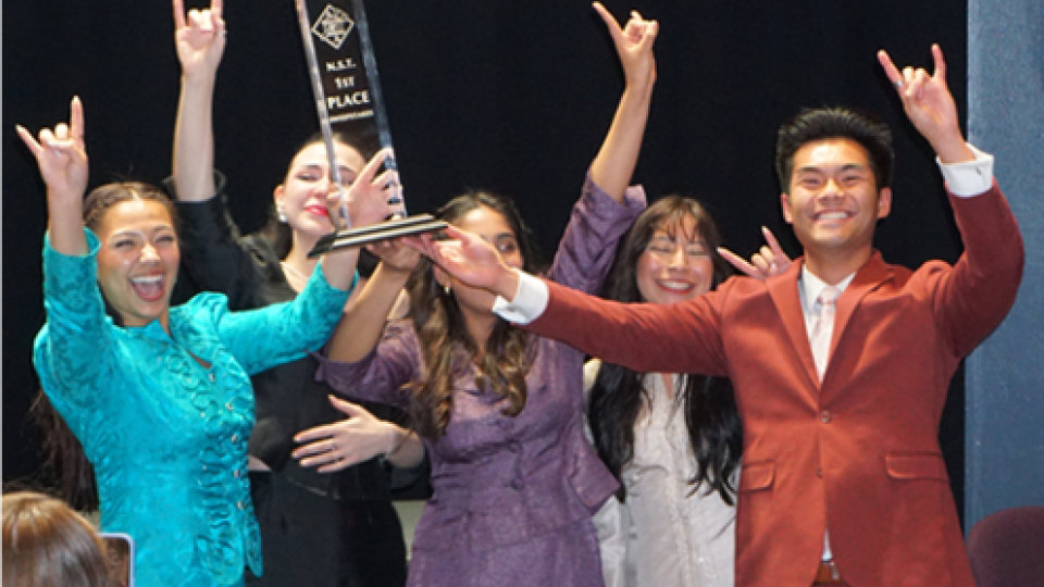 Students celebrating with a trophy.