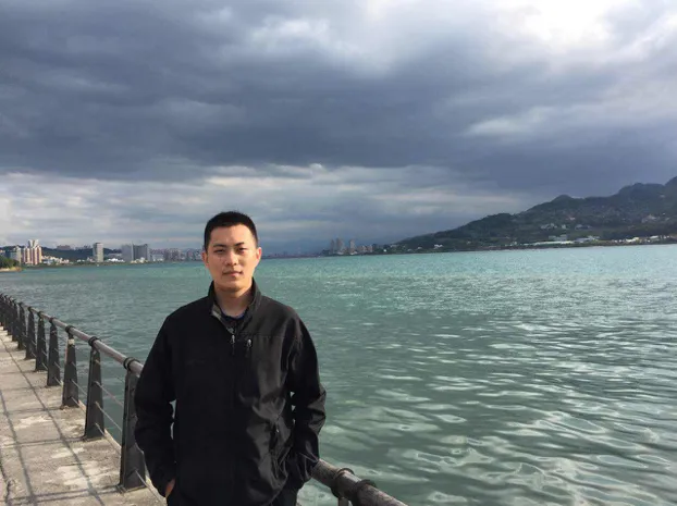 Mian Jia looks at the camera in front of a body of water