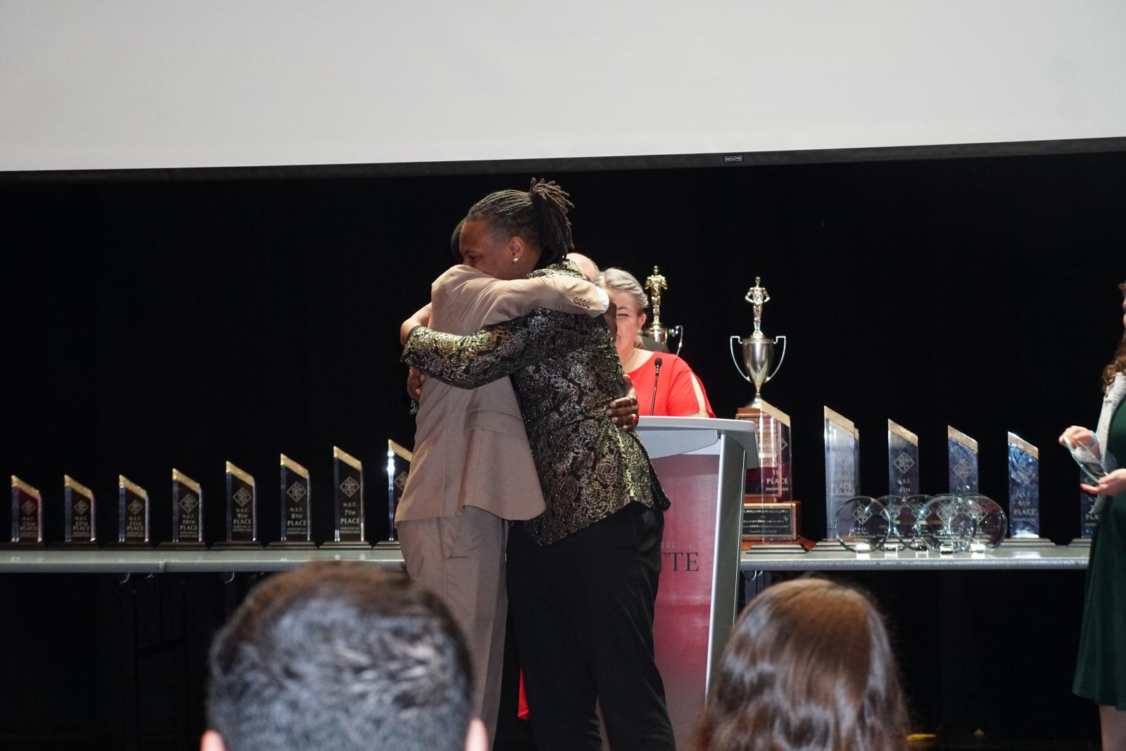 Two students hugging on the awards stage.